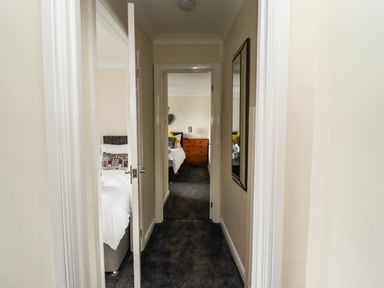 A hallway with doors leading to bedrooms and a mirror on the wall at Station View in Whitby