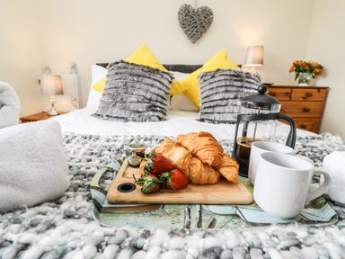A bedroom with a bed having pillows and a tray with croissants strawberries coffee press and mugs at Station View in Whitby