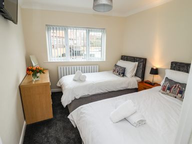 A bedroom with two single beds a wooden dresser with flowers and a lamp on a nightstand at Station View in Whitby