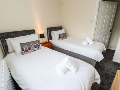 A bedroom with two single beds side by side a wooden nightstand with a lamp and a remote control Station View Whitby