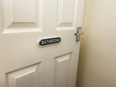 A white door with a metal handle and a bathroom sign attached to it at Station View in Whitby