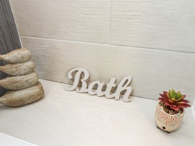 A bathroom shelf with bird decor a bath sign and a small potted plant at Station View in Whitby