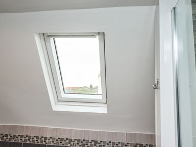 A bathroom roof window above tiled wall with mosaic border at Station View in Whitby