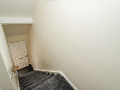 A stairwell with gray carpeted stairs leading down to a closed white door at Station View in Whitby
