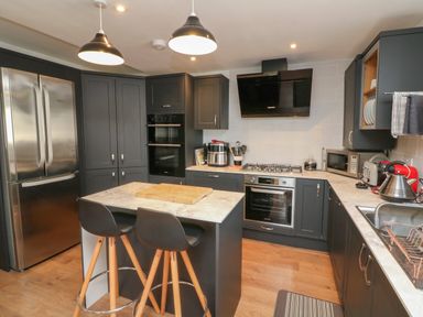 A kitchen with dark cabinets stainless steel appliances and two bar stools at Scenic Views in High Bickington