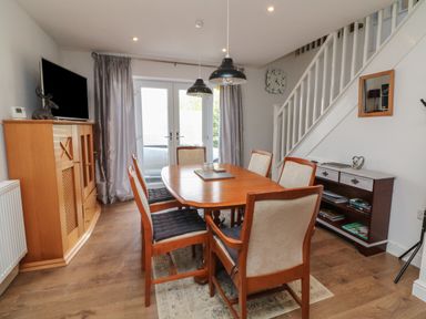 A dining room with a wooden table and six chairs near French doors at Scenic Views High Bickington