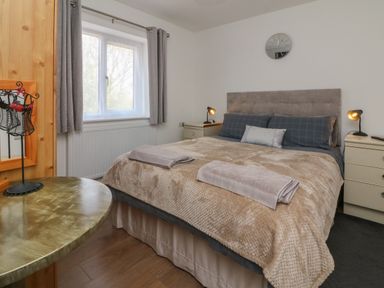 A bedroom with a double bed bedside tables with lamps a window with curtains and a round table at Scenic Views in High Bickington