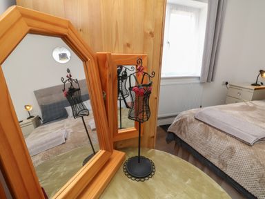 A bedroom with a bed bedside table lamp and two wooden framed mirrors on a green table at Scenic Views in High Bickington