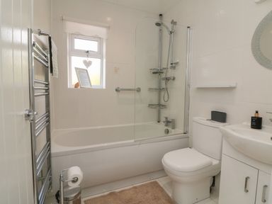 A bathroom with a bathtub shower combination a toilet a sink a window and a towel rack at Scenic Views in High Bickington