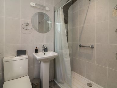 A bathroom with a toilet sink mirror and shower at Scenic Views in High Bickington