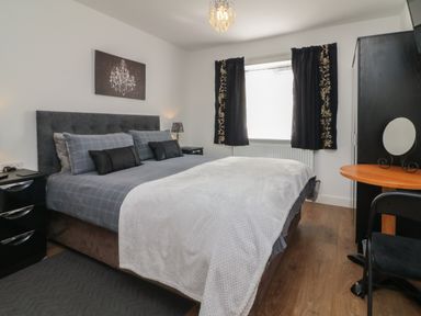 A bedroom with a bed bedside tables a window with curtains a wardrobe and a dressing table at Scenic Views in High Bickington