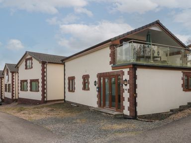 A row of beige residential buildings with brown trim and glass balcony at Scenic Views in High Bickington