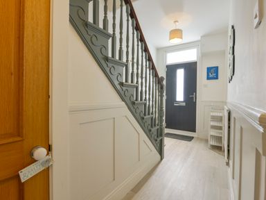 An entry hallway with a staircase and a dark front door at Beachcomber in Padstow