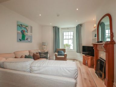A living room with a TV and a fireplace at Beachcomber in Padstow