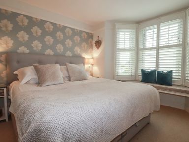 A bedroom with a large bed and a window seat at Beachcomber in Padstow