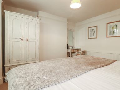 A bedroom with a bed and wardrobe at Beachcomber in Padstow