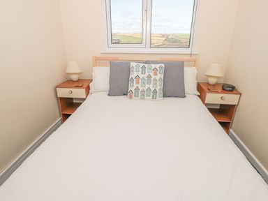 A bedroom with a bed two pillows a decorative cushion and two bedside tables with lamps at 304 Norton Park in Dartmouth