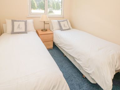 A bedroom with two single beds a nightstand with a lamp under a window at 304 Norton Park in Dartmouth