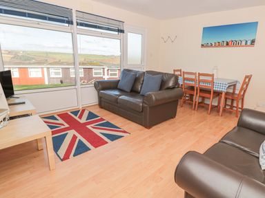 A living room with two leather sofas a table with four wooden chairs and a rug with a union jack pattern at 304 Norton Park in Dartmouth