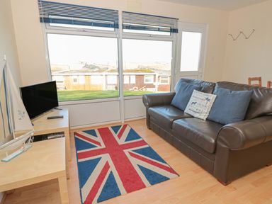 A living room with a leather sofa a union jack rug a television and a model sailboat at 304 Norton Park in Dartmouth
