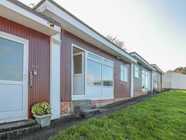 Exterior view of single-story units with numbered doors and small concrete steps at 304 Norton Park in Dartmouth