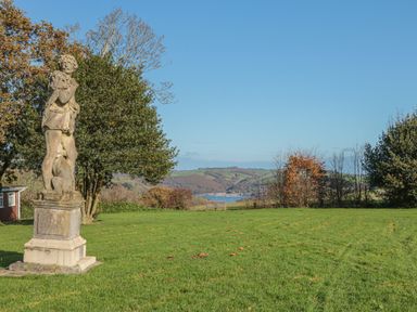 A stone statue on a grassy lawn with trees and hills and a body of water in the background at 304 Norton Park in Dartmouth