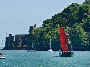 A body of water with sailboats and a castle near a tree-covered hill at 304 Norton Park in Dartmouth