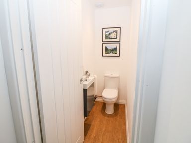 A small bathroom with a toilet and a sink with two framed pictures on the wall at Kealduff Lower in Glenbeigh County Kerry
