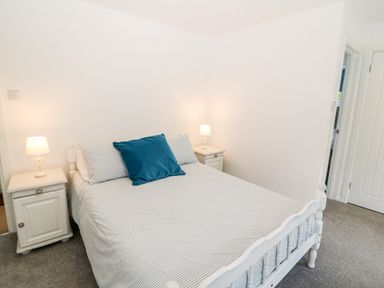 A bedroom with a bed a blue cushion two bedside tables with lamps and a door at Kealduff Lower in Glenbeigh County Kerry