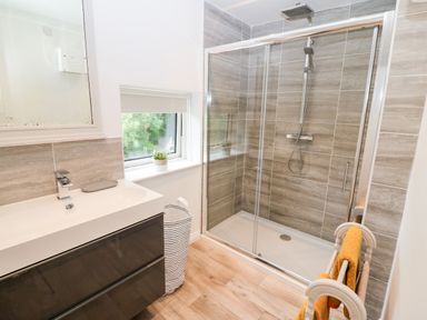 A bathroom with a glass shower enclosure a sink with a cabinet a window and a towel rack at Kealduff Lower in Glenbeigh County Kerry
