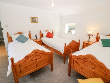 A bedroom with three wooden beds and colorful pillows at Kealduff Lower in Glenbeigh County Kerry