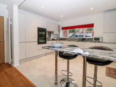 A kitchen with white cabinets black stools and a marble countertop at Casalmare in Exmouth