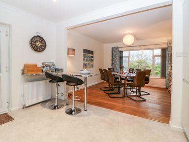 A dining room with a table set for six chairs and a breakfast bar with two stools at Casalmare in Exmouth