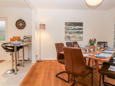 A dining area with a wooden table set with plates and glasses and a flower pot on the table at Casalmare in Exmouth