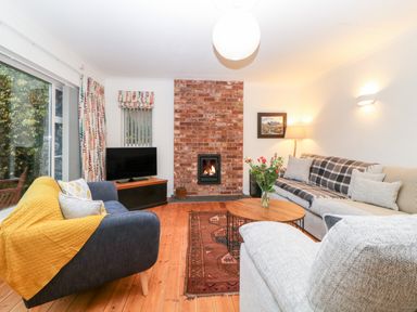 A living room with a brick fireplace a television two sofas a wooden coffee table and a rug at Casalmare in Exmouth
