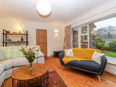 A living room with two sofas a wooden coffee table with flowers and a bookshelf at Casalmare in Exmouth