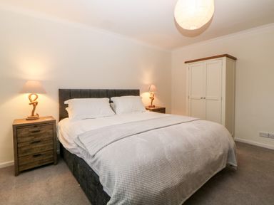 A bedroom with a double bed a wardrobe and two bedside tables with lamps at Casalmare in Exmouth