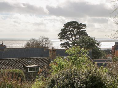 View of rooftops trees and sea under a cloudy sky at Casalmare in Exmouth