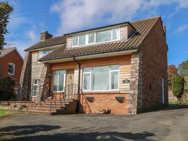 A brick and wood paneled house with steps and metal railing leading to the front door at Casalmare in Exmouth