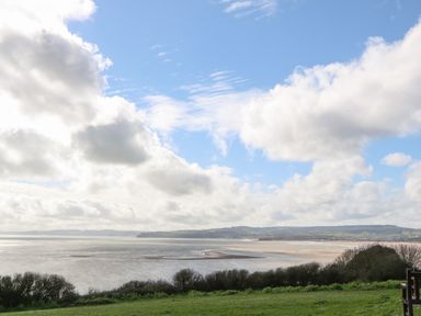 A coastal view with water grassy area and clouds in the sky at Casalmare in Exmouth