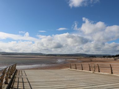 A boardwalk with railings leading to a sandy beach and a cloudy sky at Casalmare in Exmouth