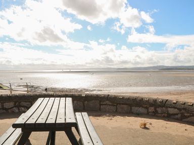 A picnic table and bench facing a beach with a stone wall at Casalmare in Exmouth