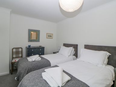 A bedroom with two single beds a dresser a wooden chair and framed pictures on the wall at Casalmare in Exmouth