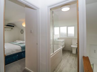 A hallway showing a bedroom with a bed and a bathroom with a bathtub and toilet at Casalmare in Exmouth