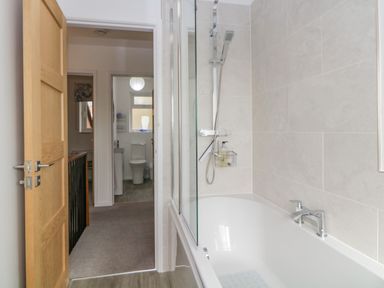 A bathroom with a bathtub and shower next to a corridor with a view into another bathroom at Casalmare in Exmouth
