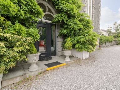 A black door entrance with two stone planters and green foliage around at Capel Mawr Basement 19 in Llanrug