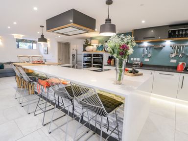 A kitchen with a large island countertop with bar stools and flowers at Capel Mawr Basement 19 in Llanrug