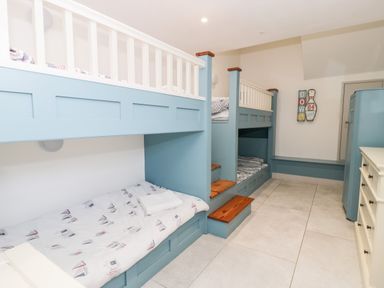 A bedroom with blue bunk beds and white dresser at Capel Mawr Basement 19 in Llanrug