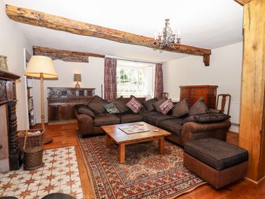 A sitting room with a large sectional sofa a wooden coffee table and exposed wooden beams at Aluric's Hall in Porlock