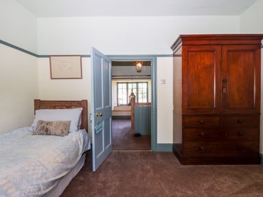 A bedroom with a single bed and wooden wardrobe at Aluric's Hall in Porlock